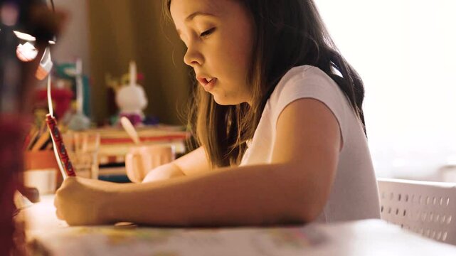 Child doing her homework at the dest at home. Education concept.