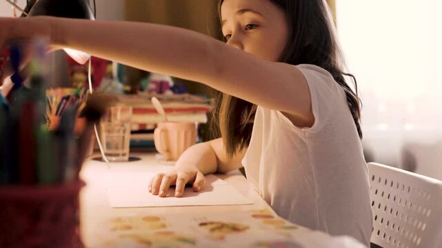 Child doing her homework at the dest at home. Education concept.