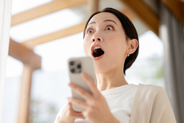 スマホを見て驚く女性