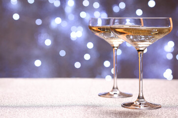 Champagne in glasses on shiny surface against blurred lights. Space for text
