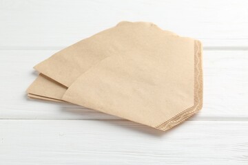 Many paper coffee filters on white wooden table, closeup