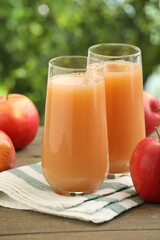 Tasty apple juice and fresh fruits on wooden table against blurred background