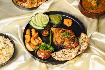 Pomfret recheado masala tandoor served with Indian tandoori bread, kulcha, rice, fish curry, chutney, and salad, arranged on a plate for a rich and flavorful traditional coastal Indian meal.
