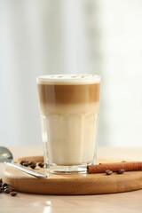 Tasty latte macchiato in glass on wooden table, closeup. Space for text