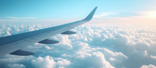 Obraz premium Airplane Wing Above Clouds in Clear Blue Sky with Copy Space for Travel and Adventure Themes