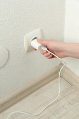 Fototapeta premium Woman plugging USB power adapter with charge cable into electrical socket indoors, closeup