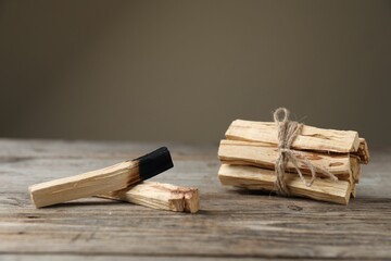 Palo santo sticks on wooden table against grey background, closeup