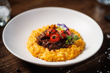 Rich saffron risotto with tender braised beef, roasted cherry tomatoes, and vibrant edible flowers. Exquisite Italian dish presented beautifully for a fine dining experience