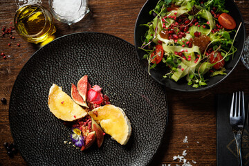 Elegant cheese dish with figs and edible flowers. Fresh mixed salad with tomatoes and greens. Fine dining experience in a modern restaurant. Healthy and delicious gourmet meal closeup