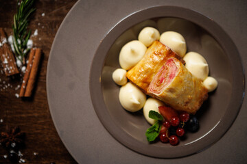 Puff pastry dessert with berry filling. Served with vanilla cream dollops, fresh red currants, blueberries, and mint leaves. Delicious gourmet dessert closeup in modern cuisine restaurant