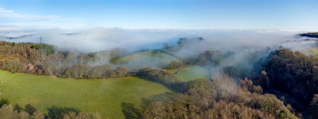 English countryside aerial panoramic wide angle picture. Rural fields with early morning mist rolling across the Devon landscape.