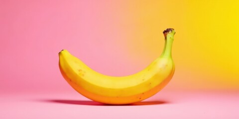 A Single Ripe Yellow Banana on a Pink and Yellow Gradient Background