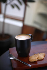 Hot Cappuccino coffee with black cup on old wooden table with isolate in black background