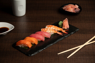 Nigiri platter with two pieces each of prawns, tuna, and salmon, served with wasabi, pickled ginger, soy sauce, and chopsticks for an elegant Japanese dining presentation. © Lucky Tony 
