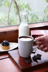 Hot chocolate with art in a white glass cup . The chocolate is sprinkled with some grated dark chocolate.