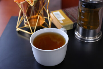 A cup of hot tea with black background, wood background, with a cup of hot tea in hand ,warm photo.