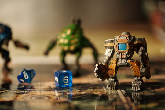 Toy warrior standing on tabletop game picture with blue cube dices with numbers against other figurines