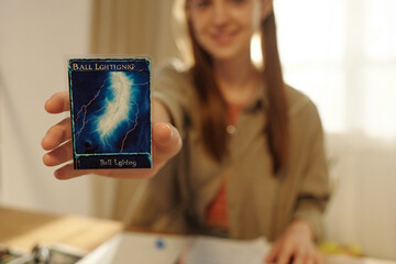 Focus on hand of young female participant of board game showing you card representing her role character