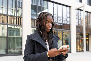 African American businesswoman checking smartphone outdoors