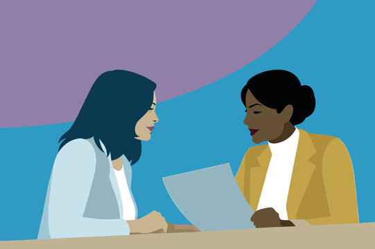 Two women engage in a business discussion, reviewing a document together at a table