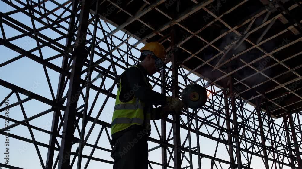 Poster in the large building construction in front of the camera constructor worker using disc welding mach