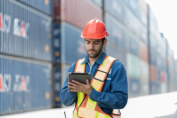 Male worker working with digital tablet at container cargo site control loading containers boxes and checking up goods and shipping containers. Cargo, logistics and shipping concept