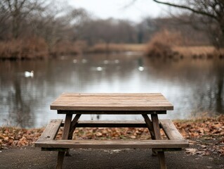 Obraz premium Wooden picnic table by a calm pond with ducks swimming, creating a peaceful and inviting scene in natural light