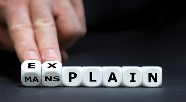 Hand turns cube and changes the expression 'mansplain' to 'explain'.