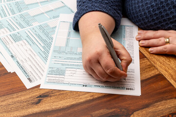 Woman completes US 1040 income tax form at home focusing on financial details and savings strategies