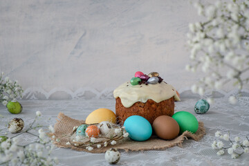 Easter cake decorated with chocolate eggs, colored eggs on a lace white tablecloth. Happy Easter concept. white spring flowers. soft focus. copy space,