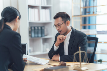 Legal Consultation: A serious and focused legal consultation takes place between a male lawyer and his client, shown reviewing important legal documents in a professional office setting.