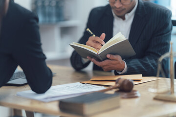 Lawyer Taking Notes: A lawyer, focused intently, writes in a notepad while consulting with a client. The image captures the seriousness and attentiveness needed for legal proceedings.