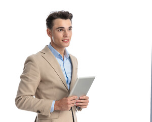 young businessman holding tablet is looking to side