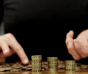 saving coins with money to pay bills having the intention of calculating raising more money to be...