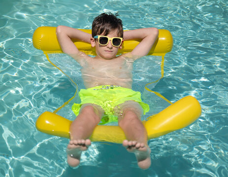 Young boy relaxing on yellow pool float in a sunny day