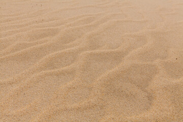A close-up shot of rippled sand with subtle footprints, showcasing the texture and natural patterns of a sandy surface.