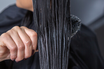 Naklejka premium Photo of a European girl with long and beautiful brunette hair at the beauty salon. Shiny and healthy hair.