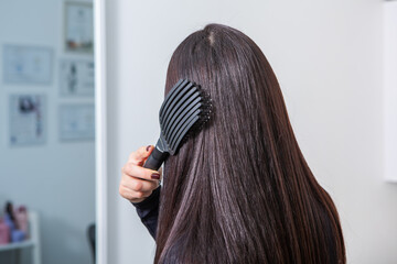 Fototapeta premium Photo of a European girl with long and beautiful brunette hair at the beauty salon. Shiny and healthy hair.