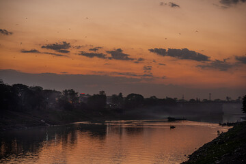 Scenic River at Sunset with Silhouetted Boats and Birds in Sylhet, Bangladesh