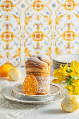 Easter cake cruffin sprinkled with powdered sugar on a festive table with painted eggs and yellow flowers. Easter treat, holiday symbol 