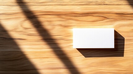 White square box on light wood with sun shadows.