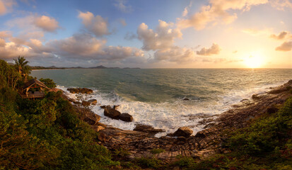 Scenic Tropical Coastline at Sunrise: Stunning Ocean View with Waves Crashing on Rocky Shoreline and Lush Greenery