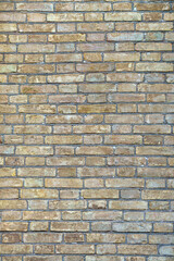 A rustic brick wall made from rectangular bricks in brown and beige. The weathered look of the bricks adds a charming and distressed aesthetic to the wall.