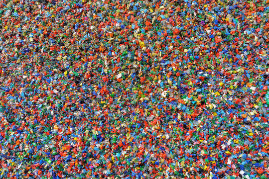 A large collection of small colorful plastic fragments. These fragments are of various shapes and sizes and are scattered densely throughout the frame.