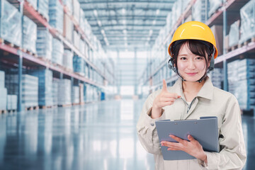 大きな物流倉庫で働くヘルメットを被った若い女性