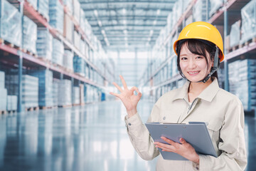 大きな物流倉庫で働くヘルメットを被った若い女性