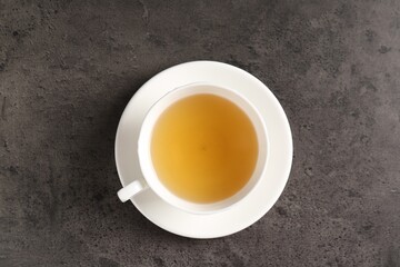 Refreshing green tea in cup on grey textured table, top view