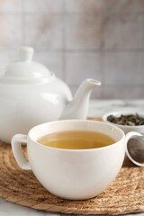 Refreshing green tea in cup on white table, closeup