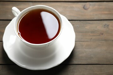 Refreshing black tea in cup on wooden table, closeup. Space for text