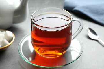 Refreshing black tea in cup on grey table, closeup